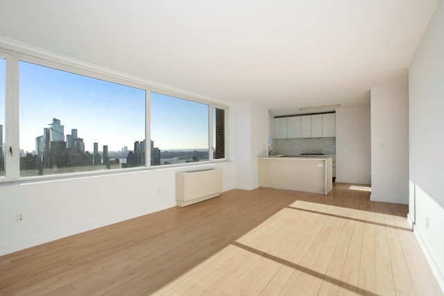 322 W 57th St Unit 55S1, New York City, NY 10019 - unfurnished living room featuring light wood-style flooring, radiator, and a view of skyline