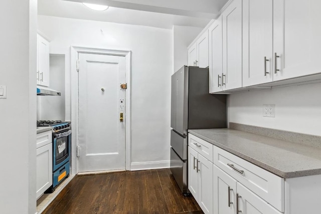 kitchen with dark wood-type flooring, stainless steel fridge, gas range oven, and white cabinets