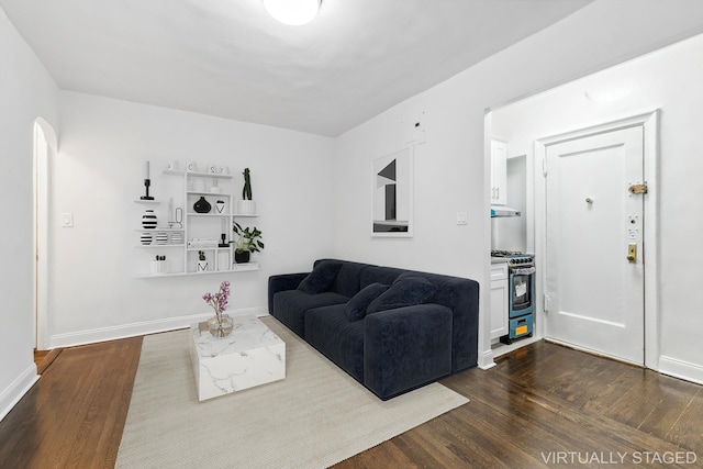 living area with baseboards, dark wood finished floors, and arched walkways