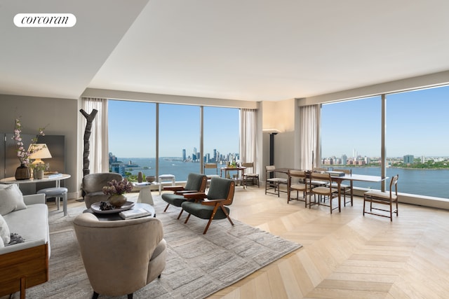 living room with visible vents, a view of city, a healthy amount of sunlight, and a water view