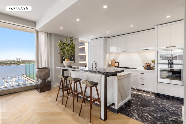 kitchen featuring a center island with sink, visible vents, gas stovetop, a kitchen breakfast bar, and modern cabinets