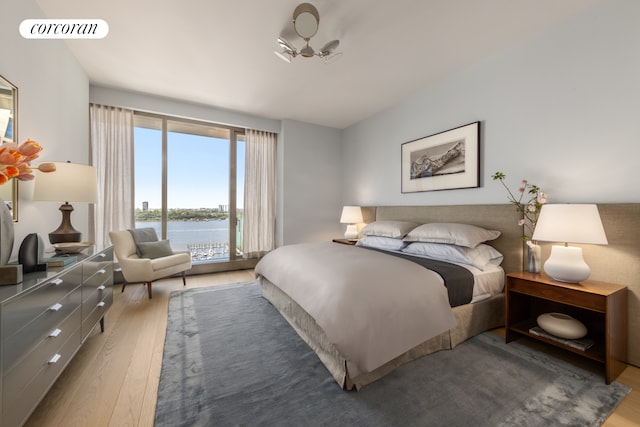 bedroom with access to outside, wood finished floors, visible vents, and a water view