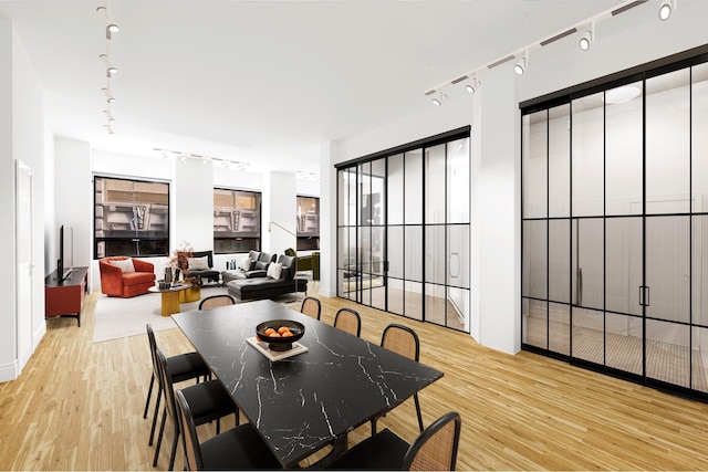 dining area with rail lighting and light wood-style floors