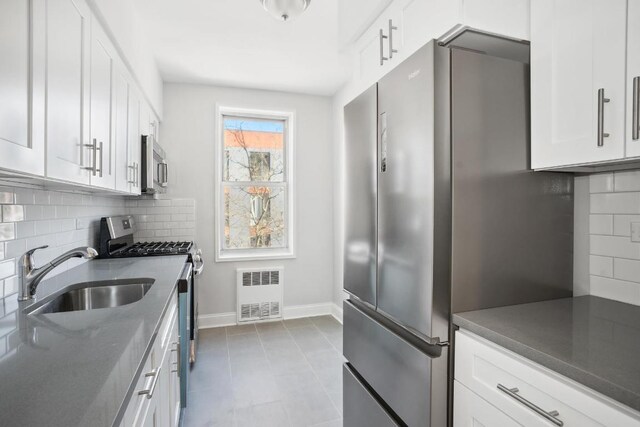 kitchen with white cabinetry, stainless steel appliances, radiator, and sink