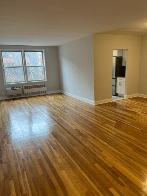 empty room with radiator, baseboards, and wood finished floors