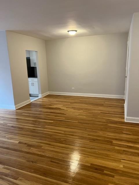 spare room with dark wood-style flooring and baseboards