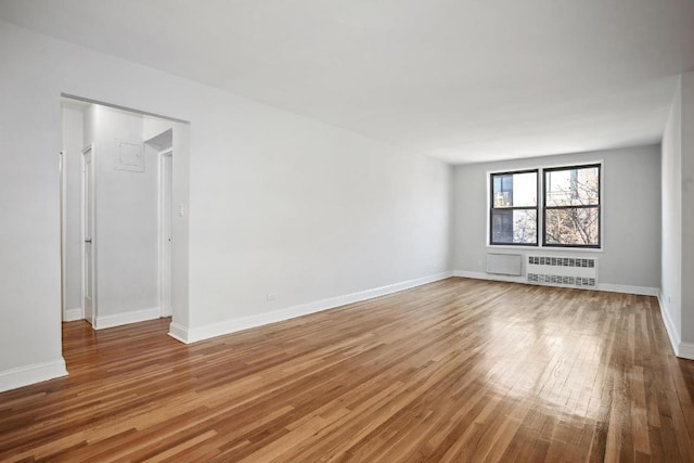 unfurnished room with baseboards, wood finished floors, and radiator