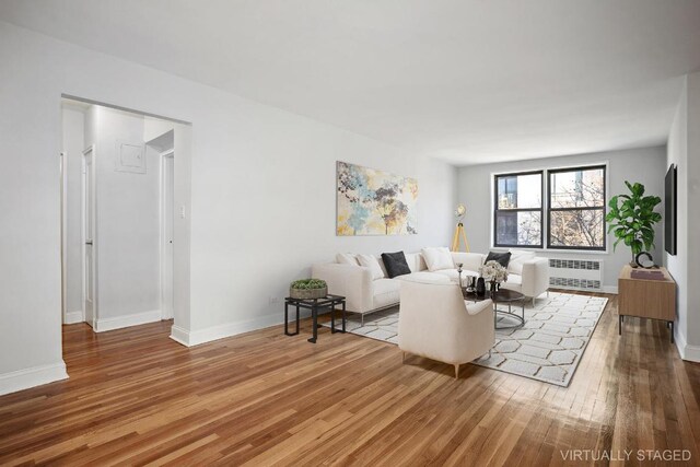 empty room with light hardwood / wood-style flooring, radiator heating unit, and an AC wall unit