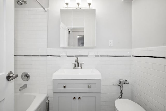 bathroom featuring toilet, bathtub / shower combination, tile walls, and vanity