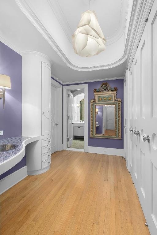 interior space with a tray ceiling, crown molding, and light hardwood / wood-style flooring