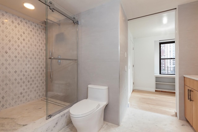 full bath featuring tile walls, tiled shower, vanity, and toilet