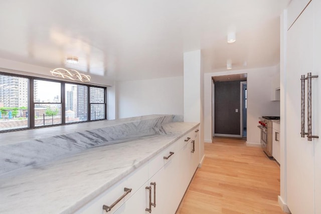 kitchen featuring light hardwood / wood-style floors, light stone countertops, white cabinets, and high end stainless steel range oven