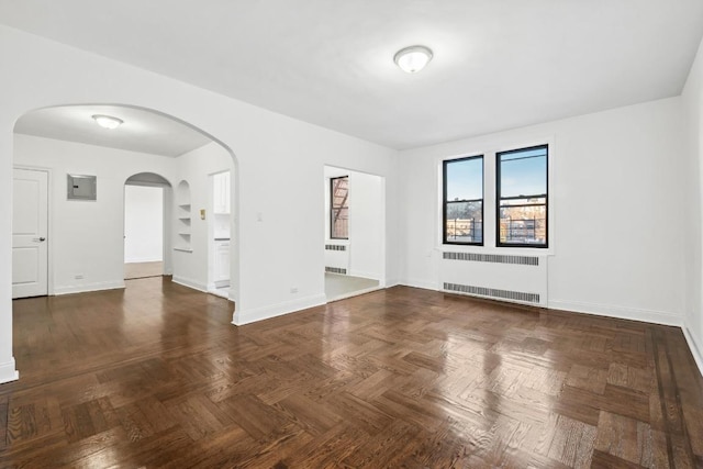 spare room with radiator heating unit and dark parquet floors