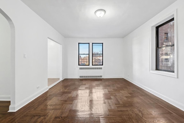 unfurnished room with dark parquet flooring and radiator heating unit