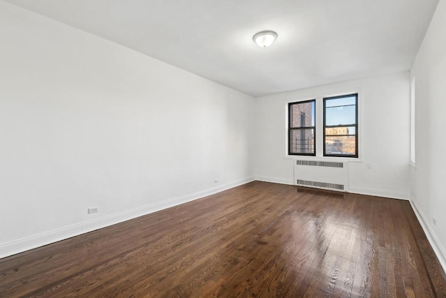 unfurnished room featuring radiator and dark hardwood / wood-style floors