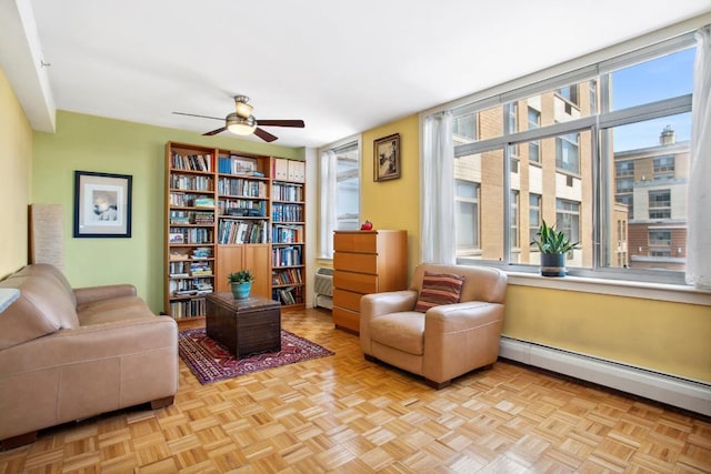 sitting room with ceiling fan, light parquet flooring, and baseboard heating