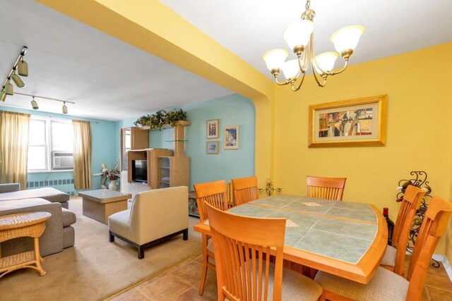 dining space featuring radiator heating unit, track lighting, an inviting chandelier, and cooling unit