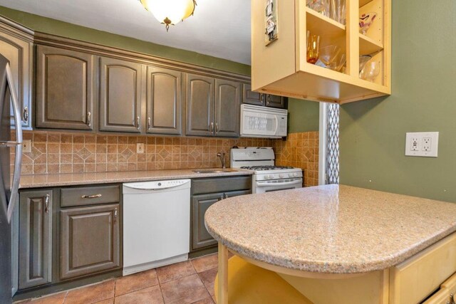 kitchen featuring white appliances, light stone counters, decorative backsplash, light tile patterned floors, and sink