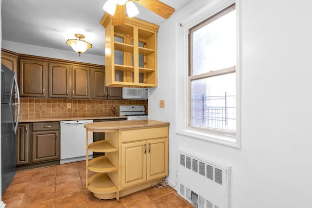 kitchen with white appliances, plenty of natural light, radiator heating unit, and decorative backsplash