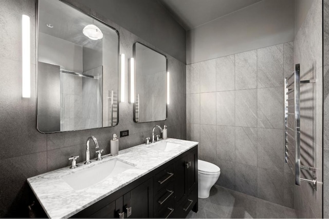 bathroom with tile walls, vanity, a shower with door, and toilet