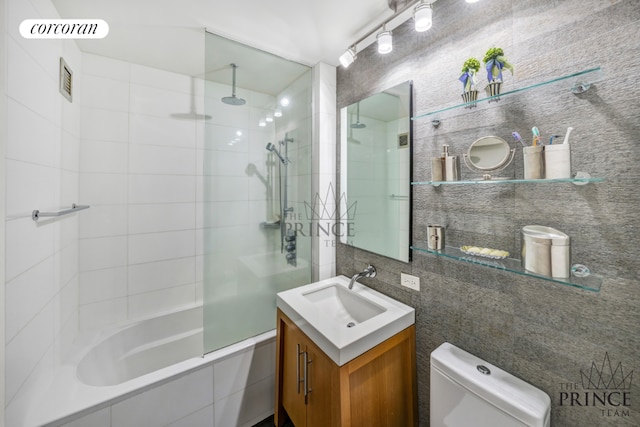 bathroom featuring visible vents, toilet, a combined bath / shower with rainfall shower, vanity, and tile walls