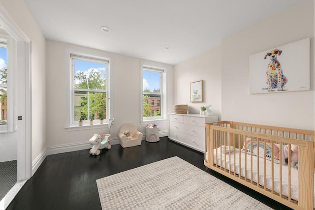 bedroom with dark hardwood / wood-style floors and a crib