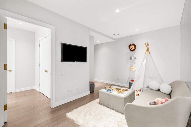 living room with a raised ceiling, floor to ceiling windows, and light hardwood / wood-style floors