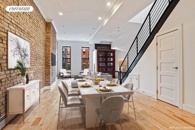 dining space with brick wall, crown molding, and light hardwood / wood-style floors