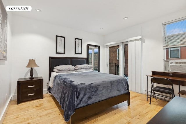 bedroom featuring baseboard heating, cooling unit, and light hardwood / wood-style flooring