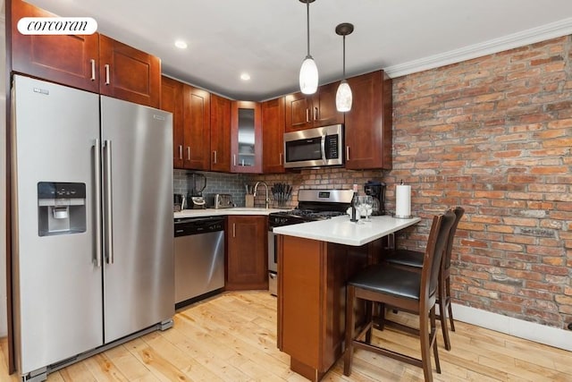 kitchen featuring a kitchen bar, kitchen peninsula, stainless steel appliances, decorative light fixtures, and sink