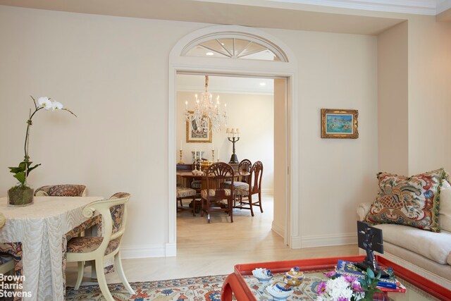 corridor with an inviting chandelier, elevator, a raised ceiling, light colored carpet, and crown molding