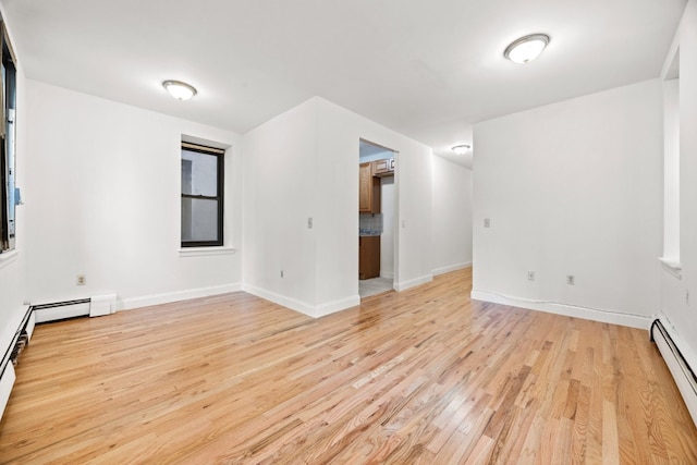 empty room with baseboard heating and light wood-type flooring