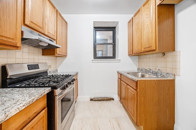 2090 Madison Ave Unit 1D, New York City, NY 10037 - kitchen with stainless steel gas range, under cabinet range hood, a sink, baseboards, and tasteful backsplash