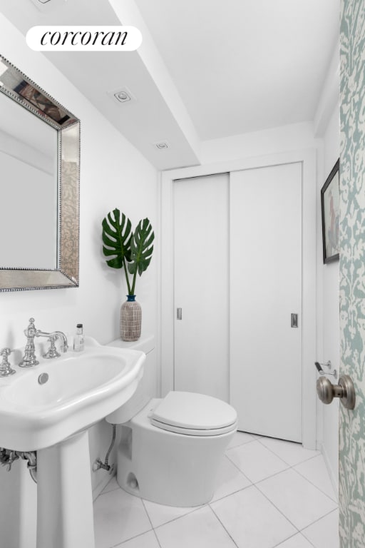 bathroom with toilet, tile patterned flooring, and sink