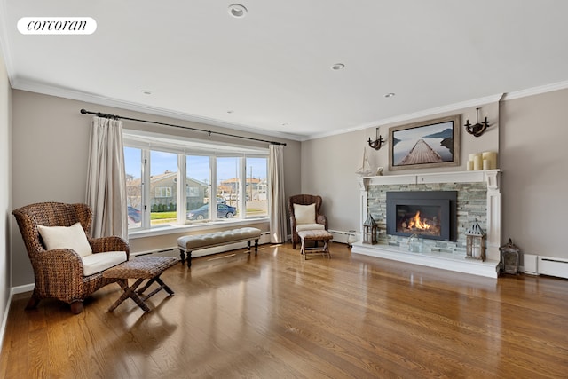 sitting room with ornamental molding, a stone fireplace, and hardwood / wood-style floors