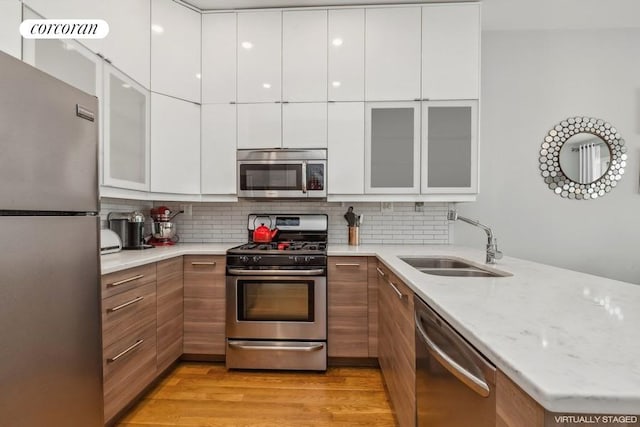 kitchen with sink, backsplash, white cabinets, and stainless steel appliances