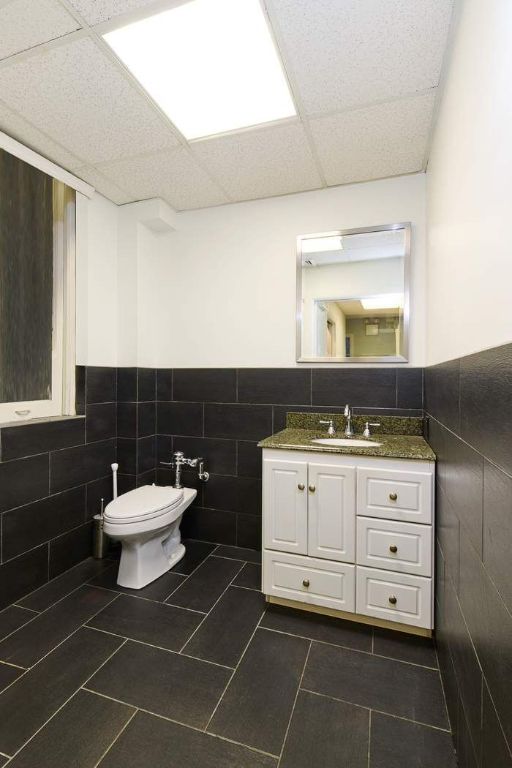 bathroom with tile patterned flooring, vanity, tile walls, toilet, and a drop ceiling