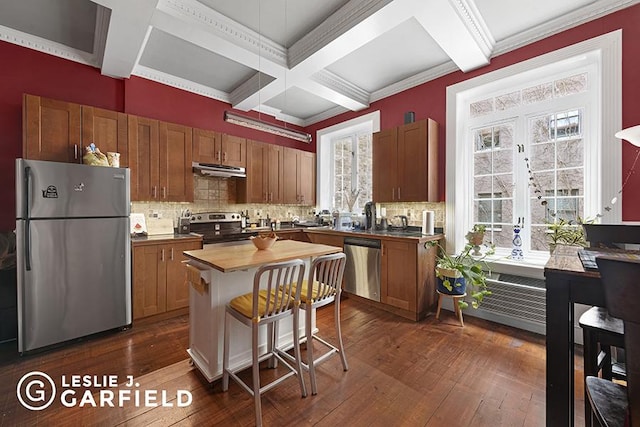 kitchen featuring appliances with stainless steel finishes, butcher block countertops, dark hardwood / wood-style flooring, coffered ceiling, and a center island