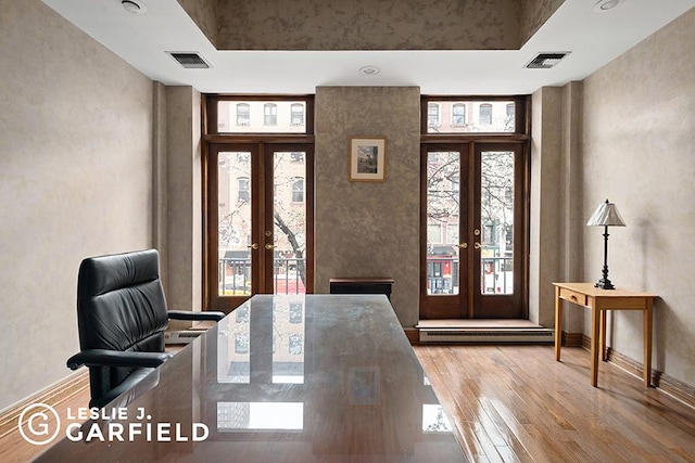 interior space with a towering ceiling, wood-type flooring, french doors, and baseboard heating