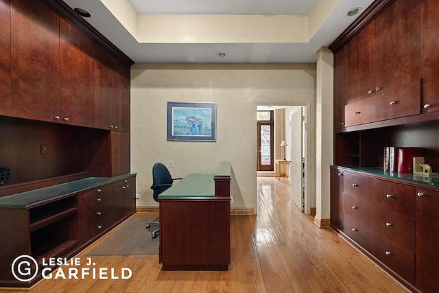 office area with a raised ceiling and light hardwood / wood-style floors