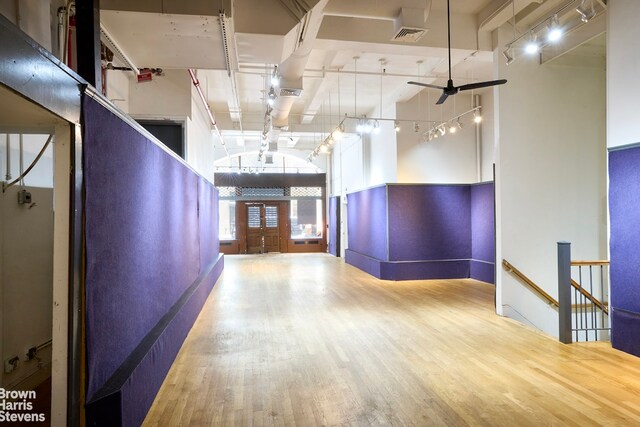 interior space featuring ceiling fan, wood-type flooring, and a towering ceiling