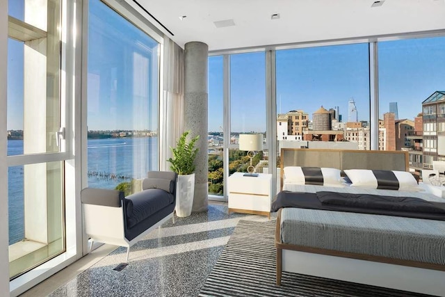 bedroom featuring a view of city, a wall of windows, and a water view