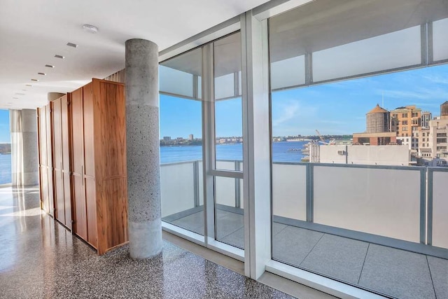 interior space featuring speckled floor, a wall of windows, a water view, and a city view