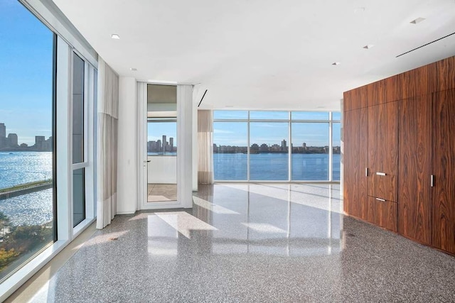 interior space with a water view, a wall of windows, and a wealth of natural light