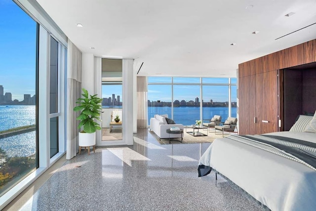 bedroom featuring speckled floor, a wall of windows, and a water view