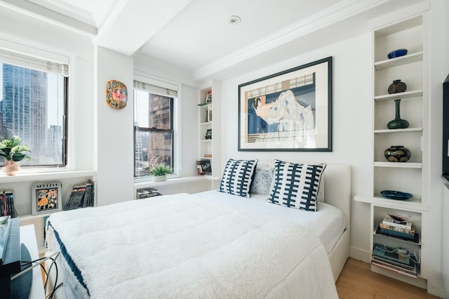 bedroom featuring crown molding, wood-type flooring, and multiple windows