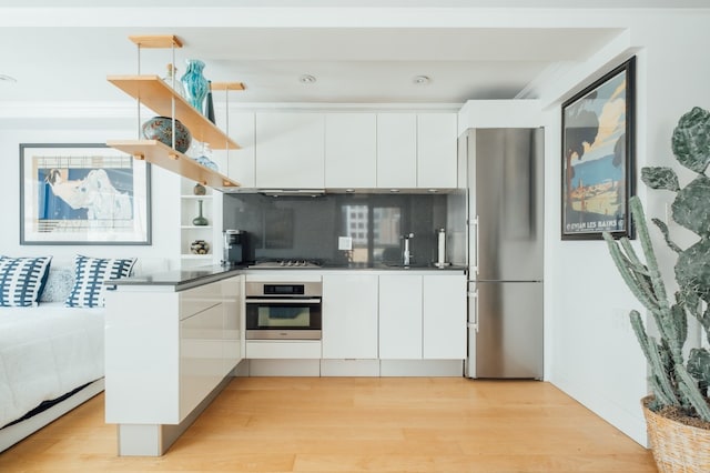 kitchen with modern cabinets, light wood-style flooring, open shelves, white cabinetry, and appliances with stainless steel finishes