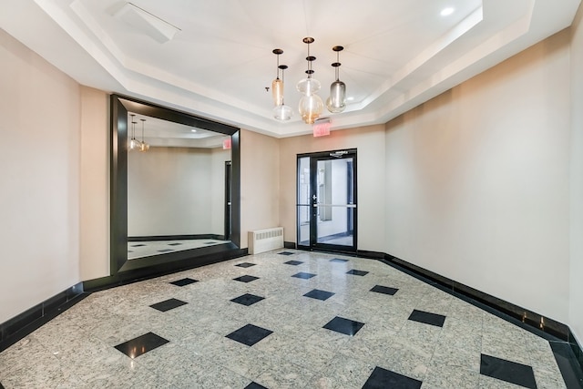 spare room with an inviting chandelier and a raised ceiling