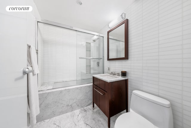 full bathroom featuring vanity, toilet, combined bath / shower with glass door, and tile walls