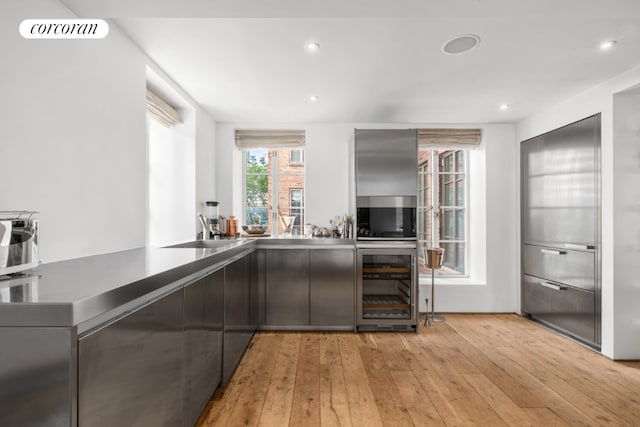 bar featuring wine cooler, sink, and light hardwood / wood-style flooring